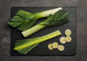 Photo of Fresh raw leeks on grey table, flat lay. Ripe onion