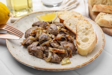 Photo of Tasty fried chicken liver with onion served on white tiled table, closeup