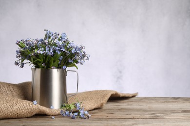 Photo of Beautiful forget-me-not flowers on wooden table against light background. Space for text