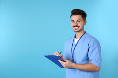 Photo of Young medical student with clipboard on color background. Space for text