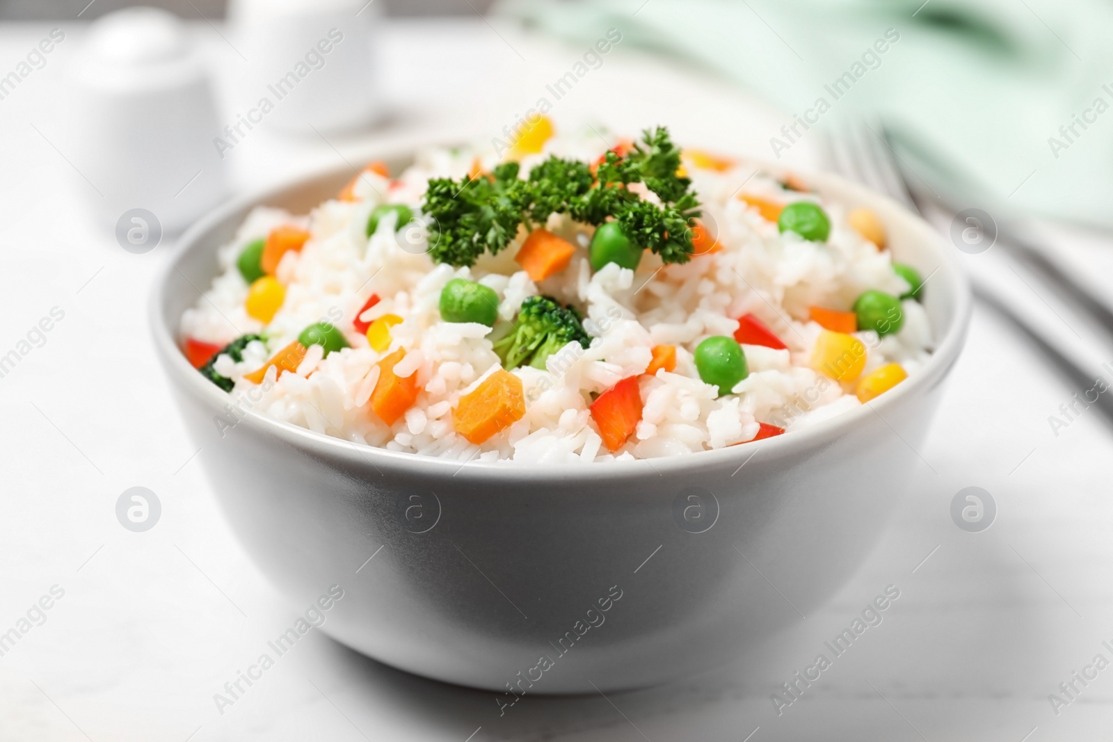 Photo of Bowl with tasty rice and vegetables on table, closeup