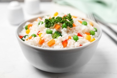 Photo of Bowl with tasty rice and vegetables on table, closeup