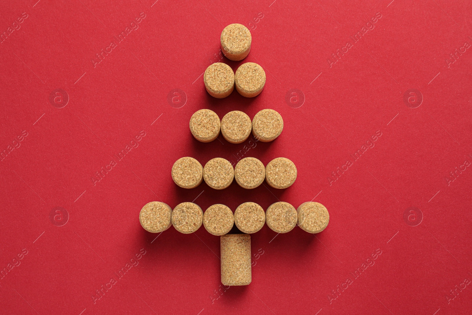 Photo of Christmas tree made of wine corks on red background, top view