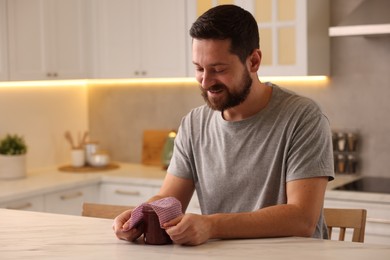 Man packing jar of jam into beeswax food wrap at table in kitchen