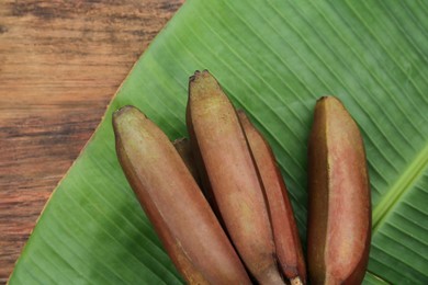 Photo of Delicious purple bananas and fresh leaf on wooden table, flat lay