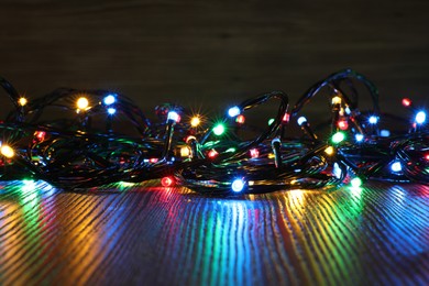 Photo of Beautiful colorful Christmas lights on wooden table