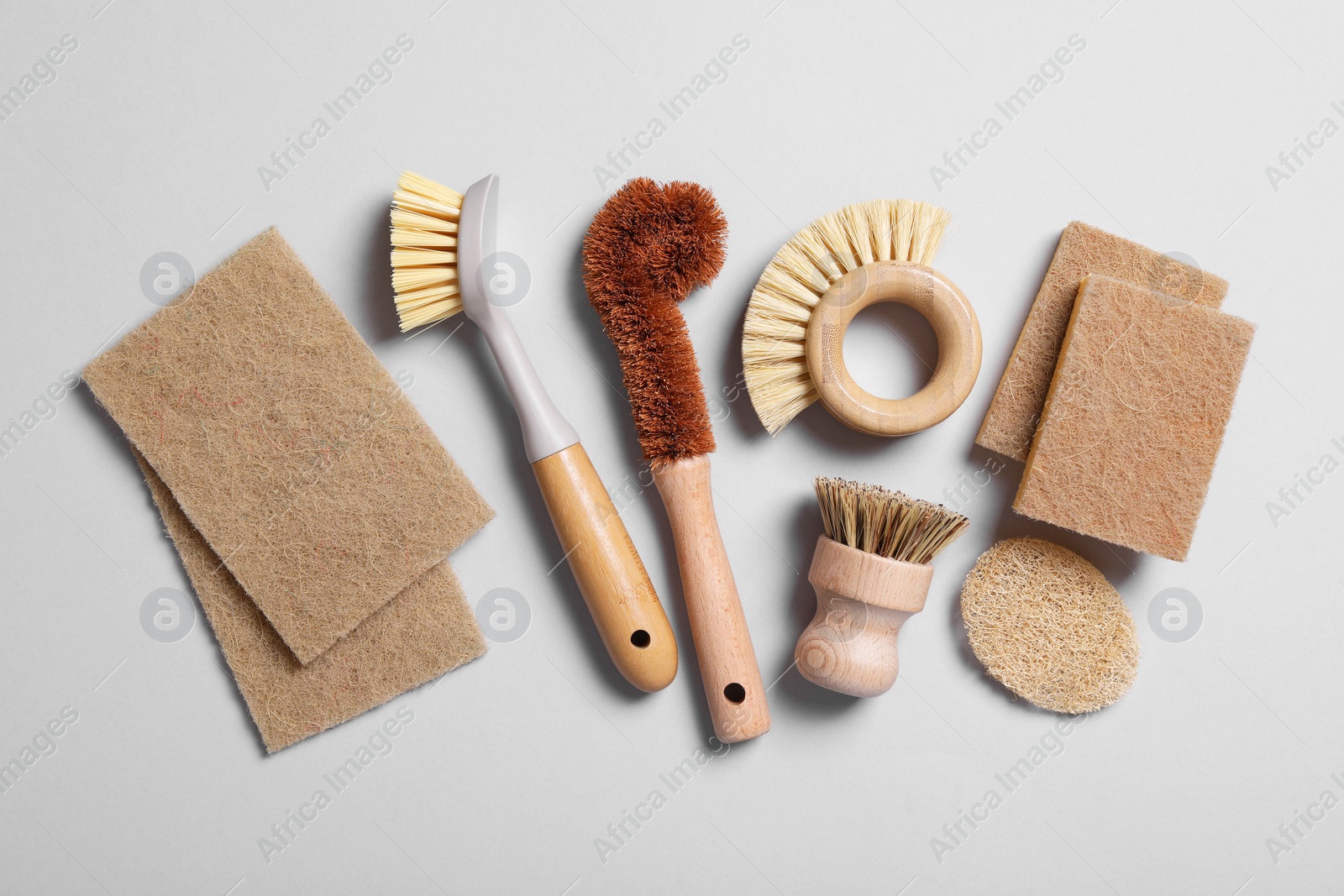 Photo of Cleaning brushes and sponges on grey background, flat lay