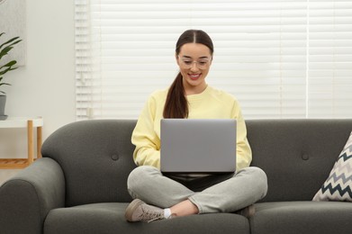 Woman using laptop on couch at home