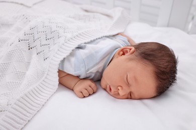 Cute newborn baby sleeping under white plaid on bed