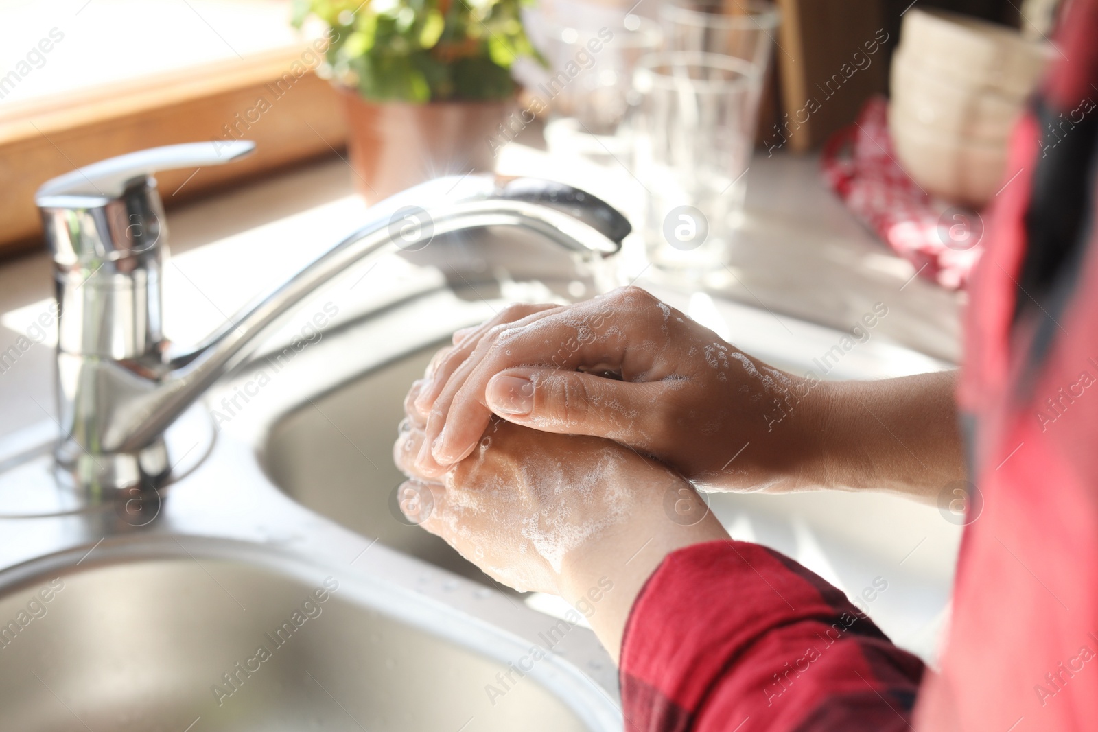 Photo of Woman washing hands in kitchen, closeup view