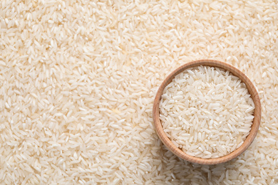 Pile of polished rice and wooden bowl, top view. Space for text