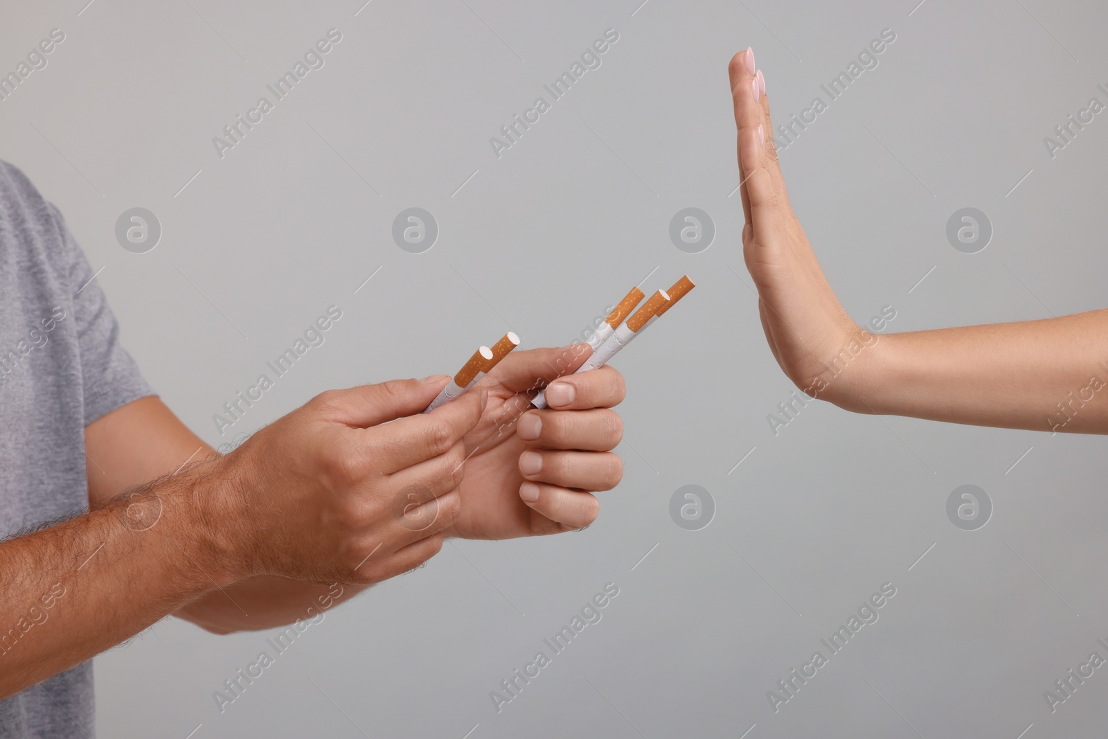 Photo of Stop smoking concept. Woman refusing cigarettes on grey background, closeup