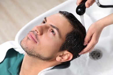 Photo of Stylist washing client's hair at sink in beauty salon