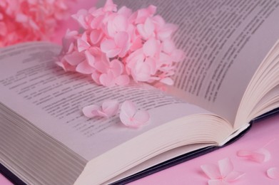 Beautiful hortensia flowers and book on pink background, closeup