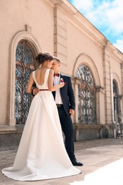 Young bride in beautiful gown with her groom outdoors