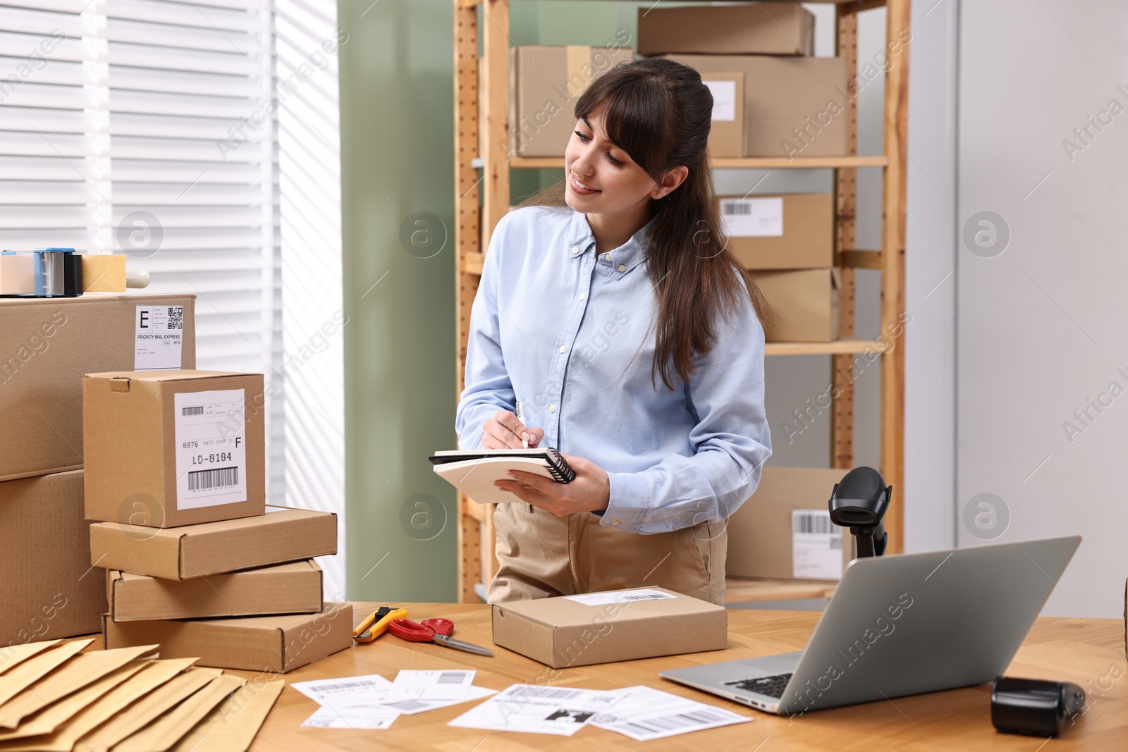 Photo of Parcel packing. Post office worker writing notes indoors