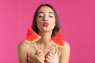 Beautiful young woman posing with watermelon on color background