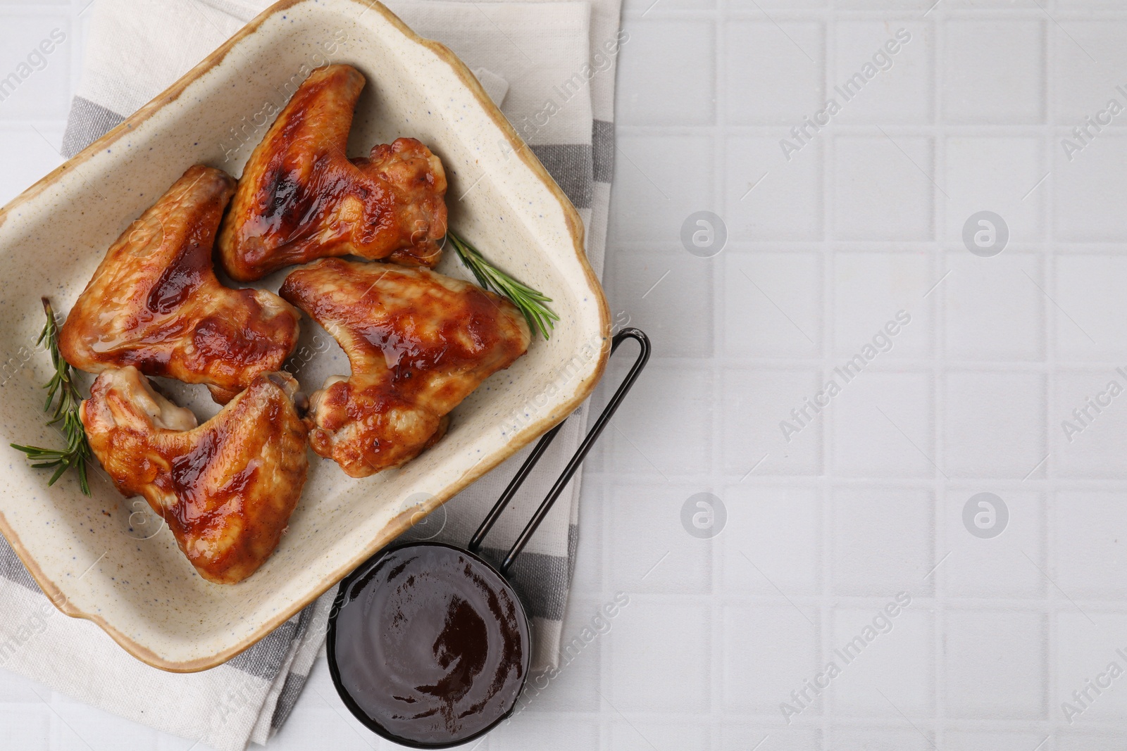 Photo of Fresh marinade, chicken wings and rosemary on white tiled table, top view. Space for text