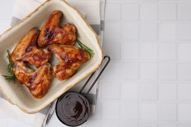 Photo of Fresh marinade, chicken wings and rosemary on white tiled table, top view. Space for text