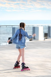 Photo of Little girl roller skating on city street