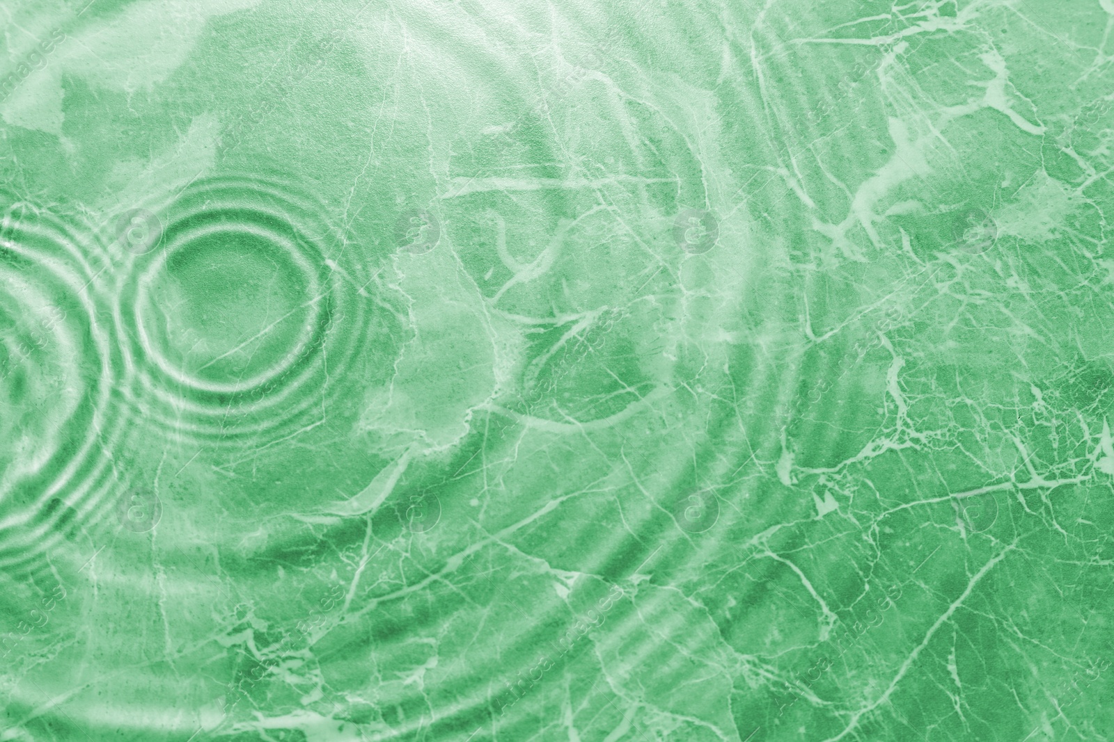 Image of Rippled surface of clear water on green background, above view