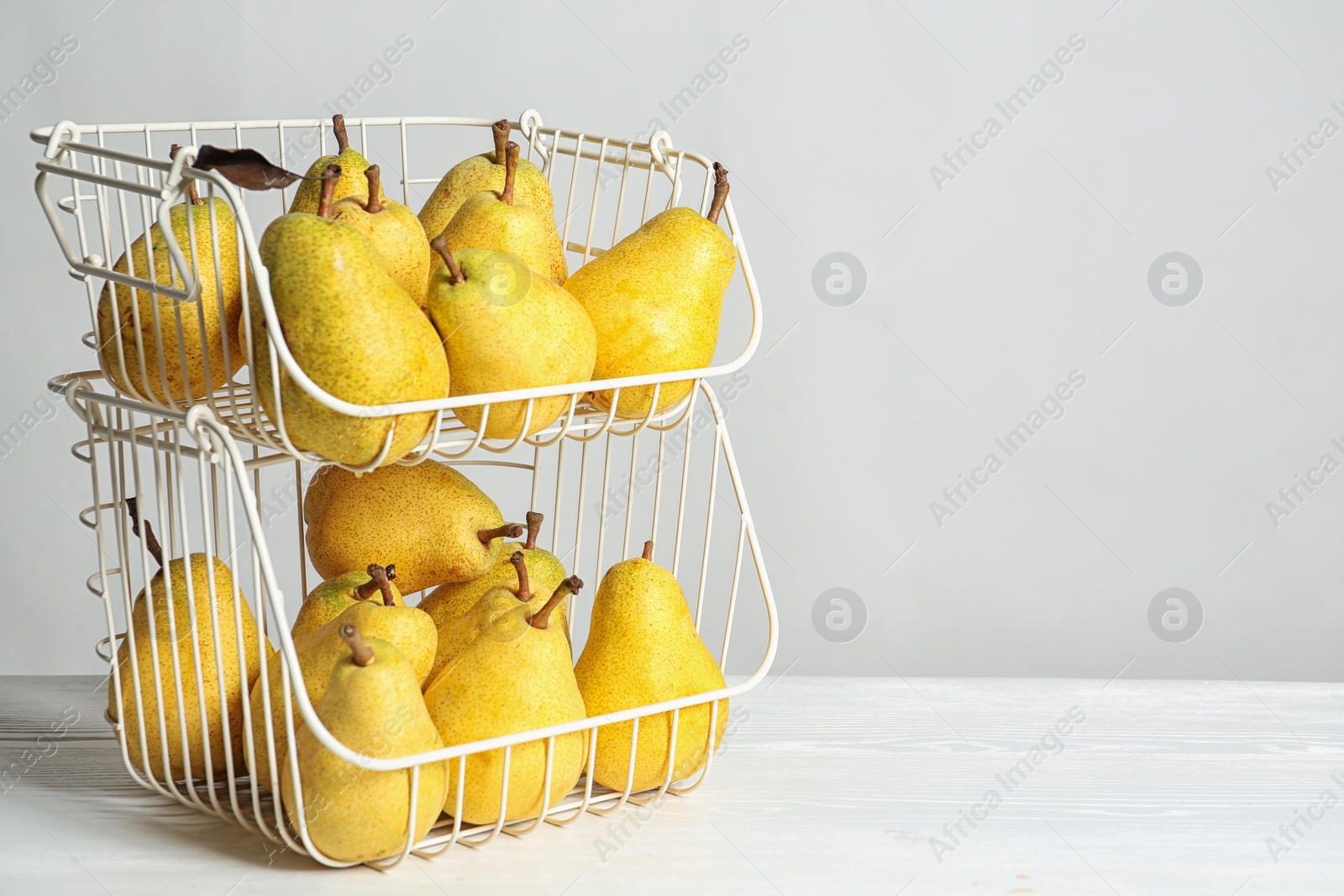 Photo of Basket of fresh ripe pears on table against light background with space for text