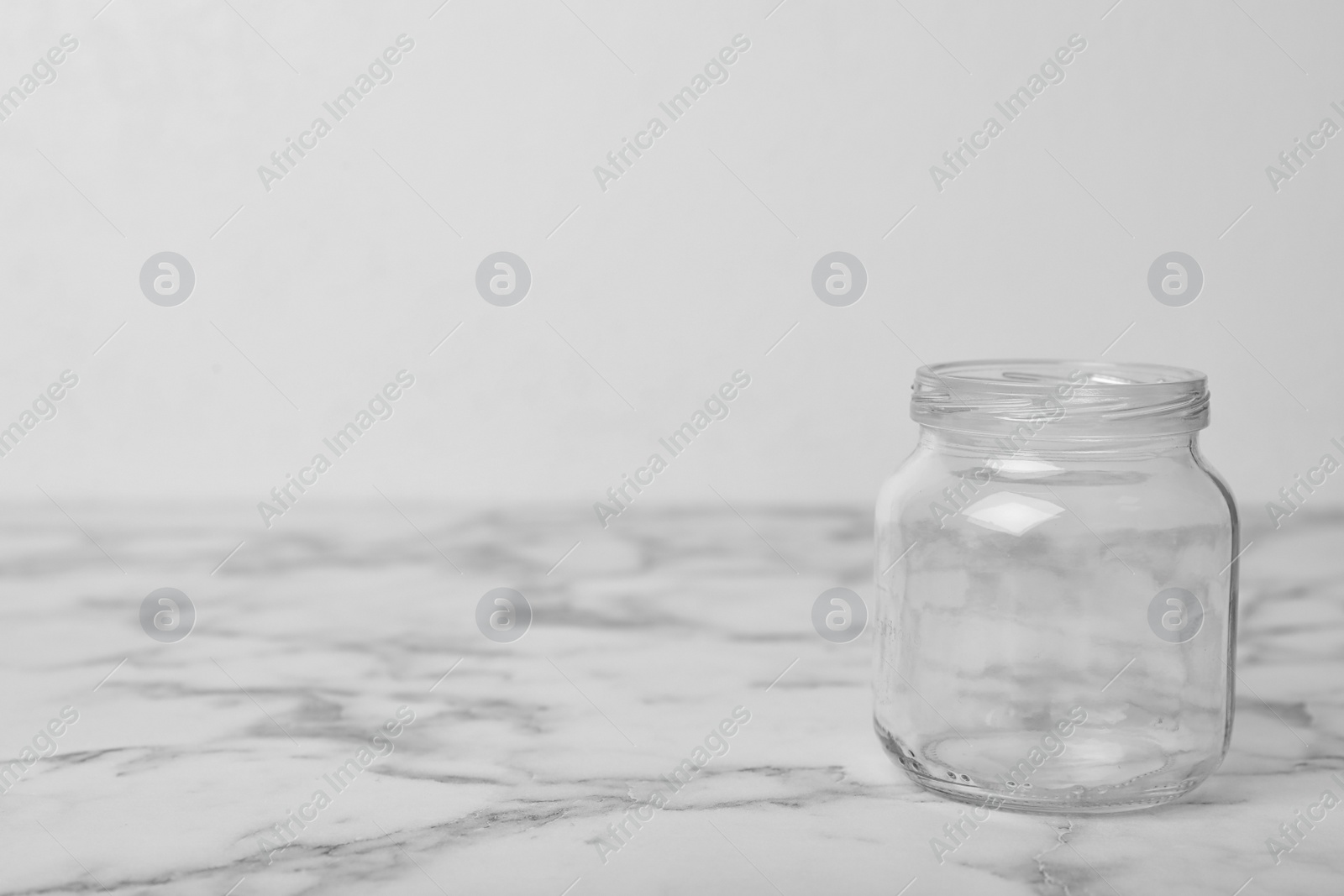 Photo of Empty glass jar on white marble table, space for text