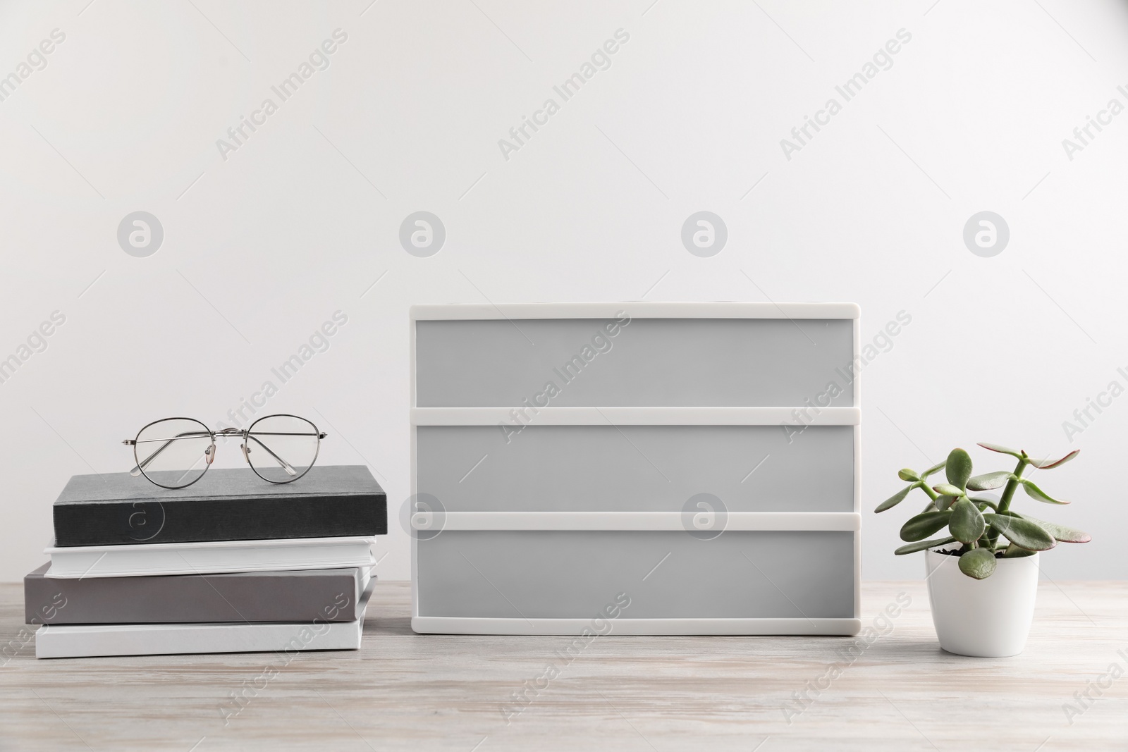 Photo of Blank letter board, books, glasses and beautiful houseplant on wooden table. Mockup for design