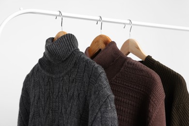 Photo of Rack with different casual sweaters on light background, closeup