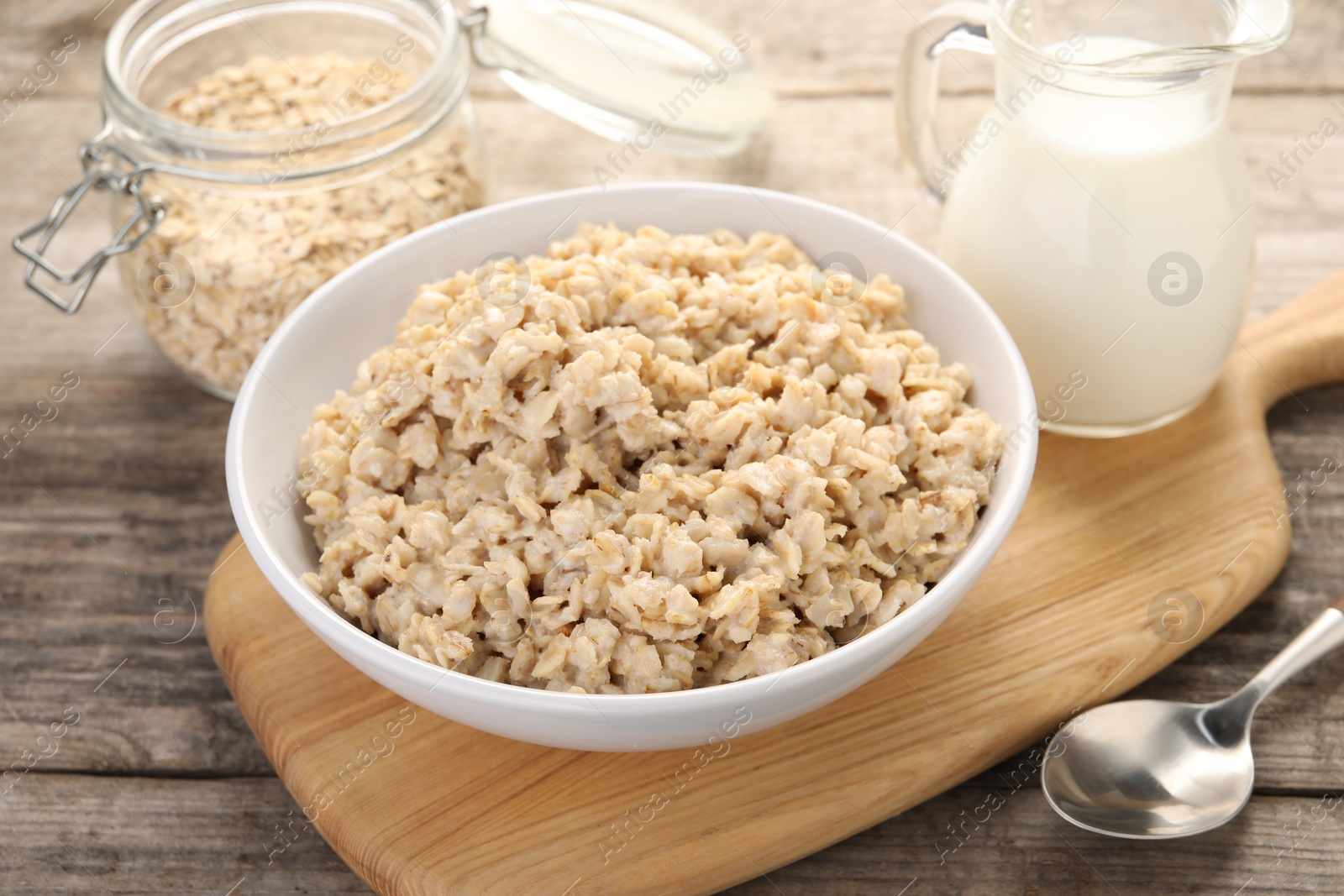 Photo of Tasty boiled oatmeal served on wooden table, closeup