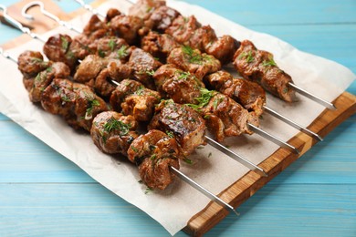 Photo of Metal skewers with delicious meat served on light blue wooden table