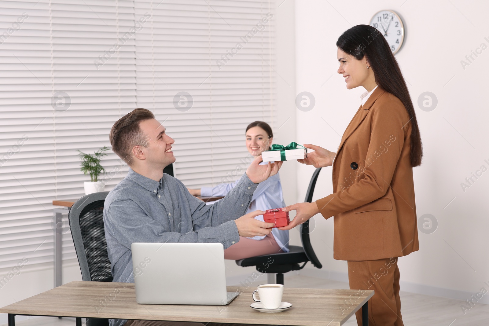 Photo of Woman presenting gift to her colleague in office