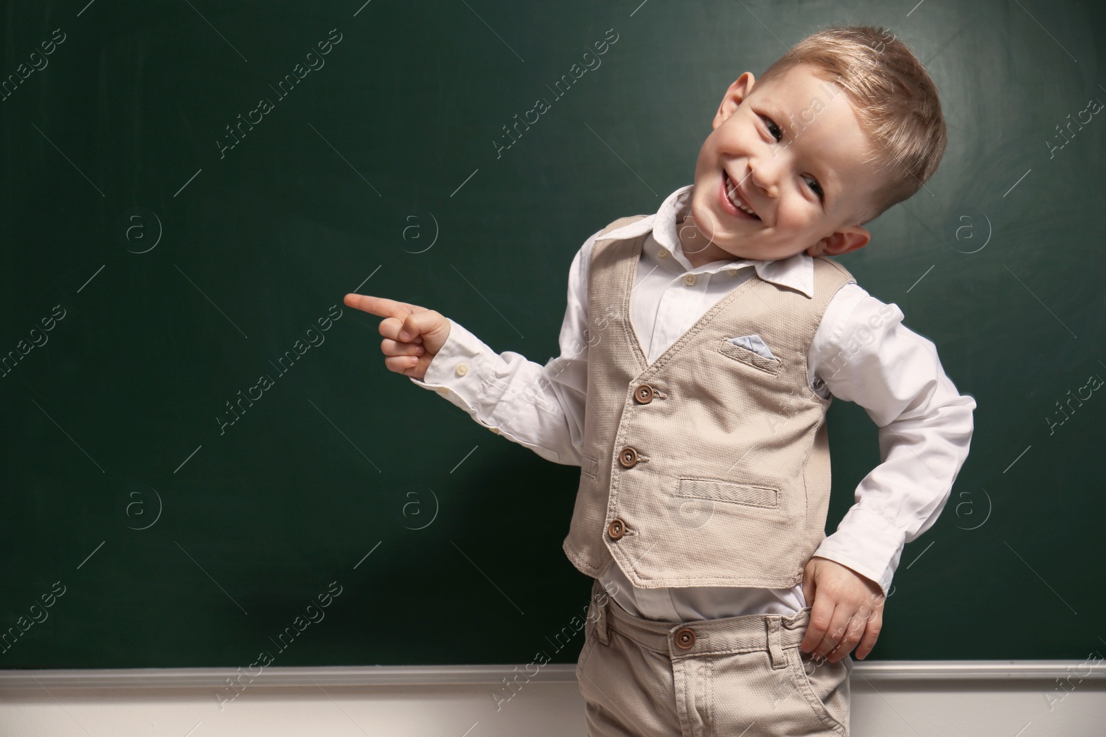 Photo of Funny little child near chalkboard, space for text. First time at school