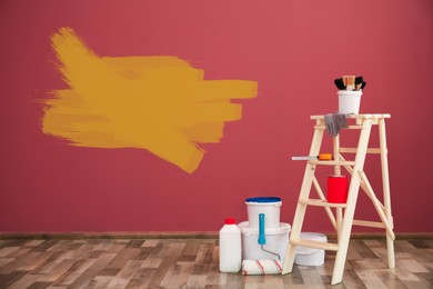 Image of Set with decorator's tools and paint on floor near color wall