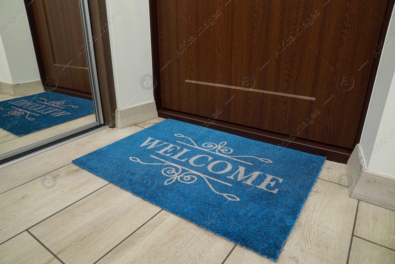 Photo of Beautiful blue doormat with word Welcome on floor near entrance