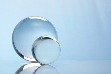 Transparent glass balls on mirror surface against light background. Space for text