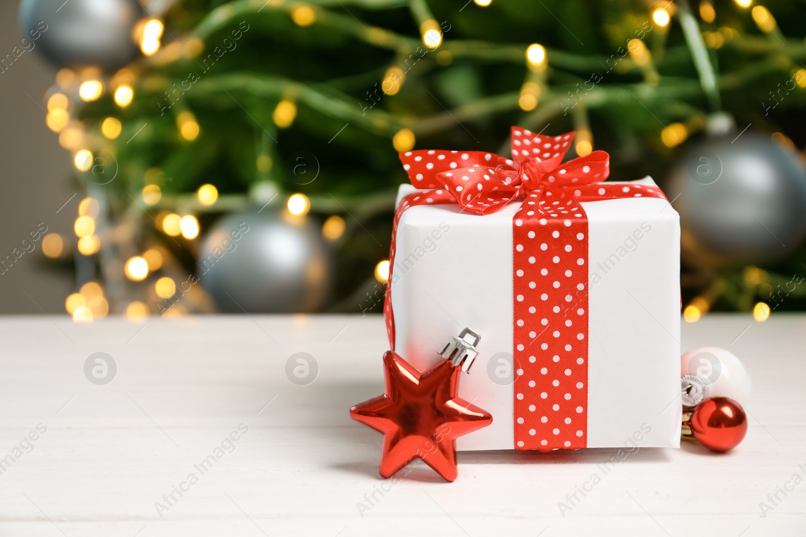 Photo of Beautiful gift box and blurred Christmas tree on background