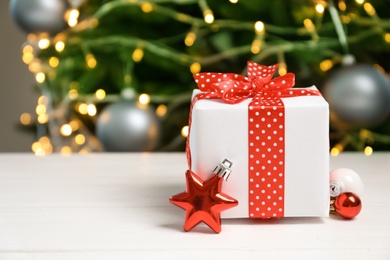 Photo of Beautiful gift box and blurred Christmas tree on background