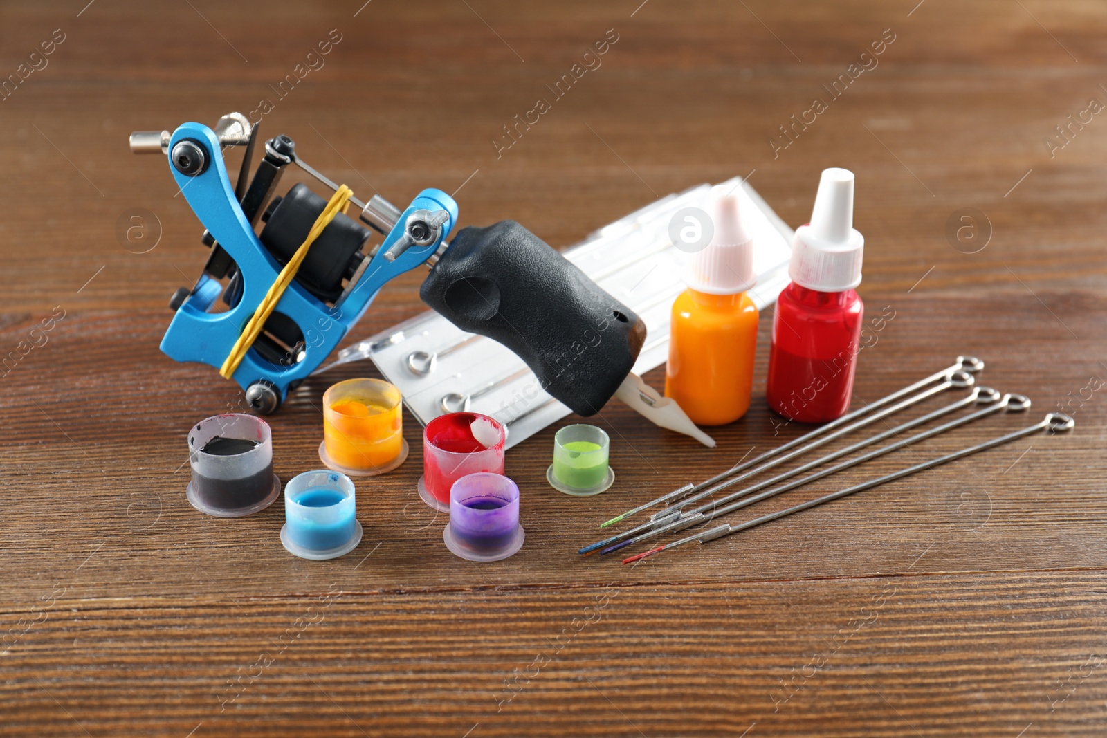 Photo of Composition with tattoo machine and needles on wooden table