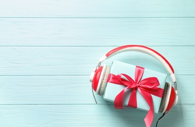 Flat lay composition with gift box and headphones on wooden background. Christmas music concept