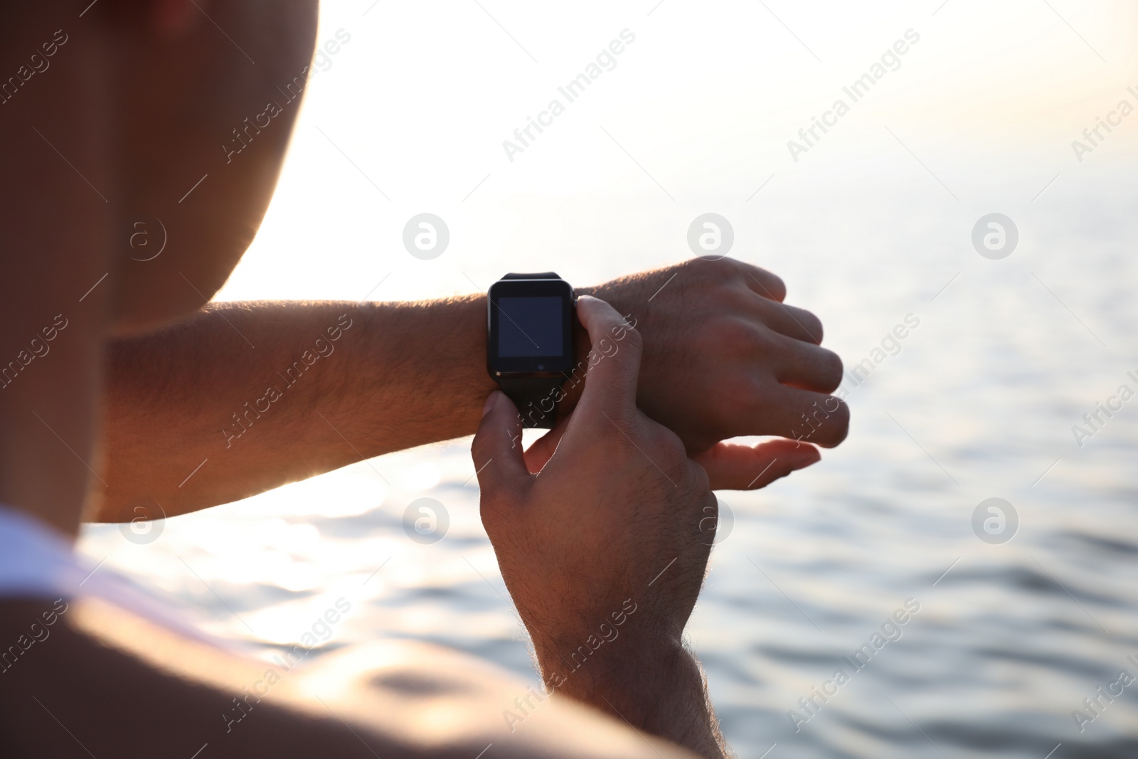 Photo of Man checking fitness tracker after training near river, closeup