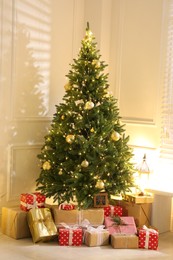 Photo of Gift boxes under Christmas tree with fairy lights indoors