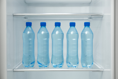 Many bottles with fresh water on fridge shelf