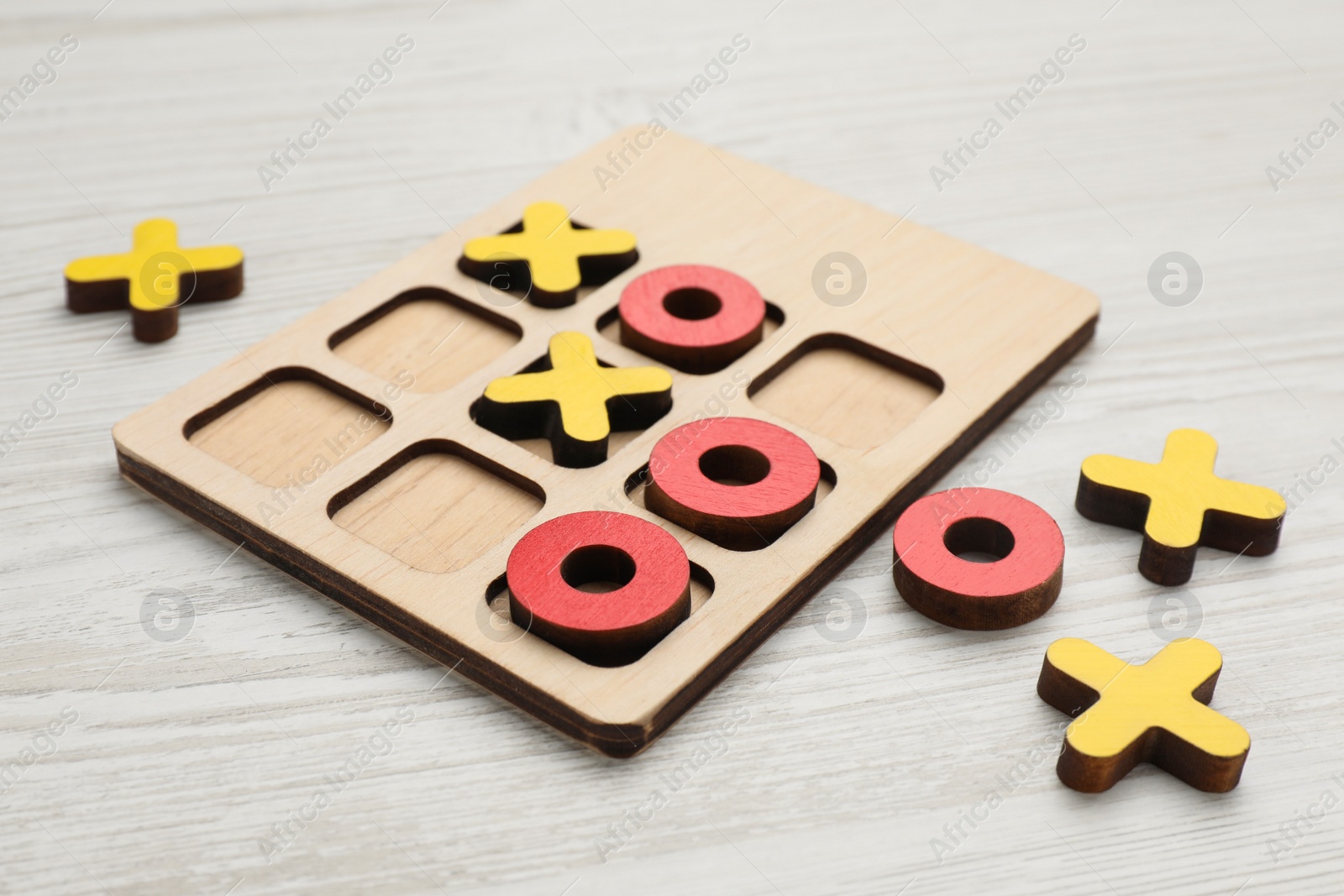 Photo of Tic tac toe set on white wooden table, closeup