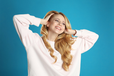 Portrait of beautiful young woman with dyed long hair on blue background