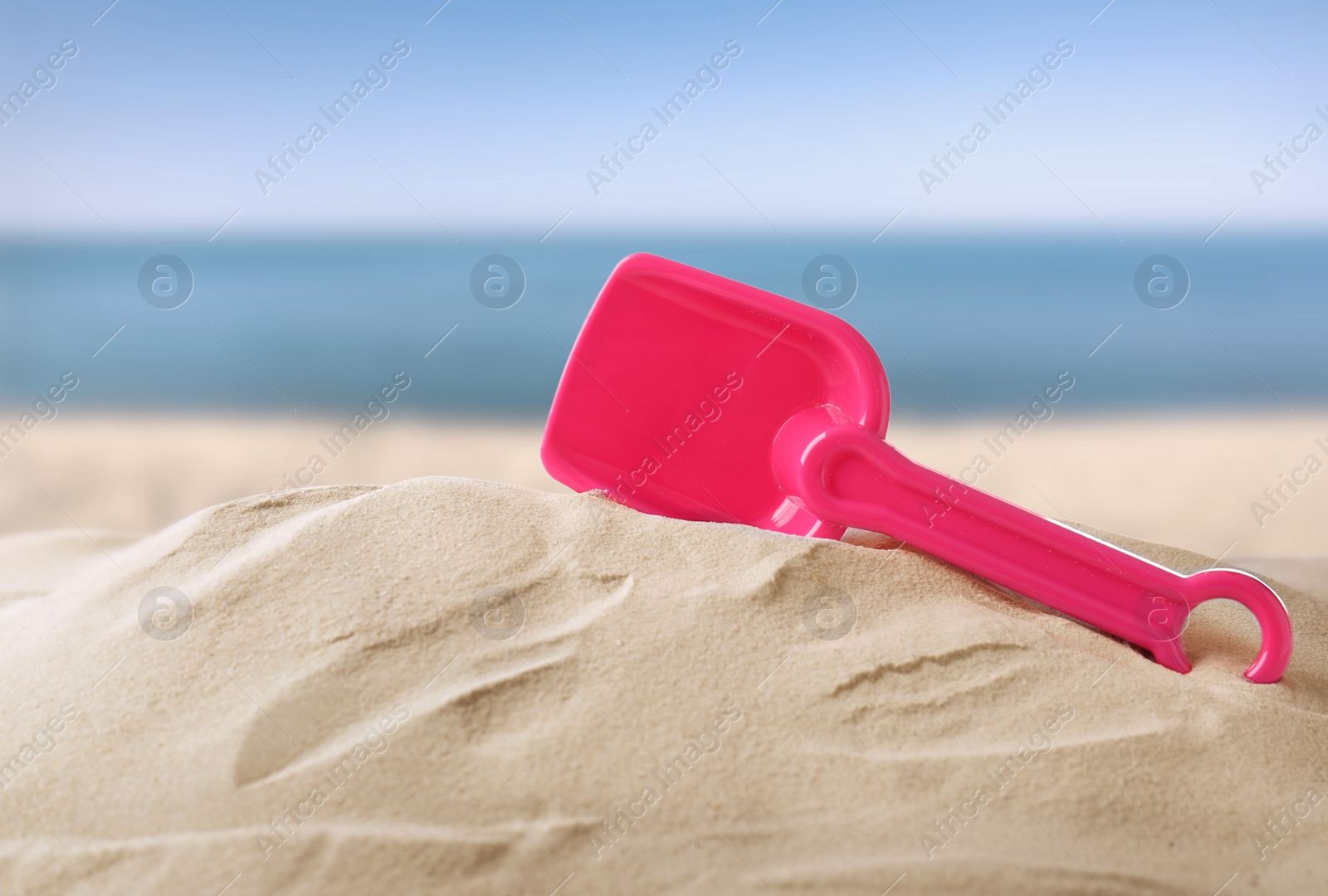 Image of Pink plastic toy shovel sandy beach near sea