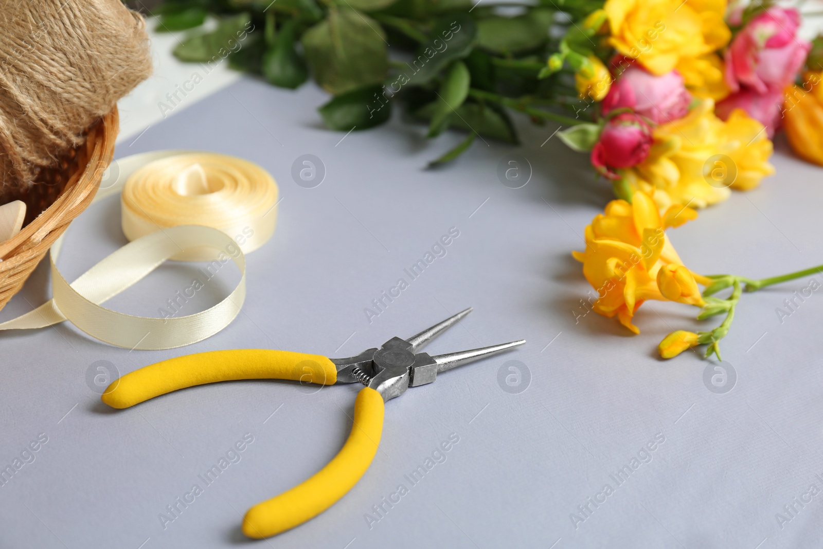 Photo of Florist workplace with pliers and flowers on table