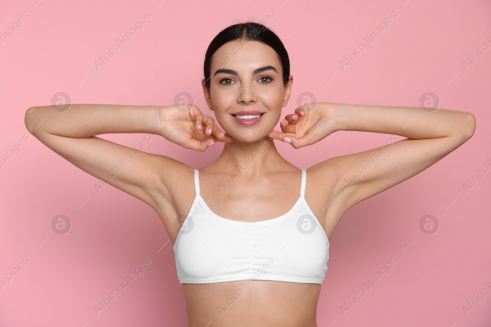 Photo of Young woman showing smooth skin after epilation on pink background