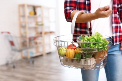 Man with shopping basket full of products in grocery store, closeup