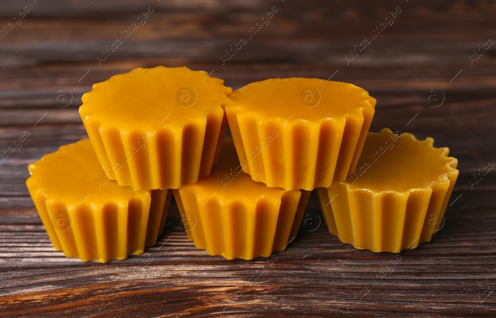 Photo of Natural beeswax cake blocks on wooden table, closeup